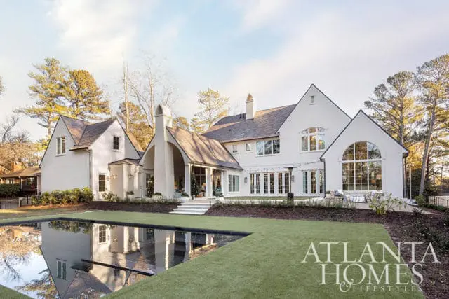 White stucco house with arched entryway and large arched window, overlooking a pool.