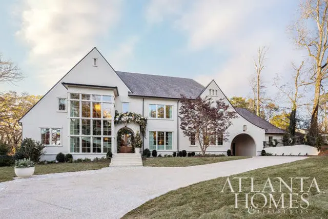 White stucco house with large windows, arched entryway, and holiday decorations.