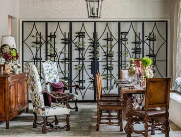 Dining room with ornate wine rack, floral upholstered chairs, and wooden sideboard.