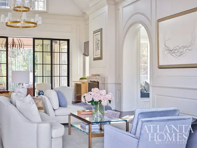 Light-filled living room with white sofas, blue accent chairs, and arched doorway.