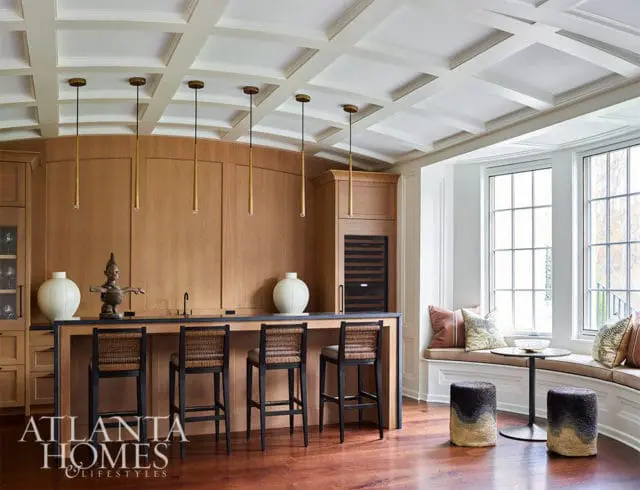 Bar area with wood paneling, woven stools, and coffered ceiling. Bay window with built-in seating.