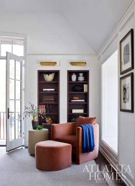 Living room with coral armchair and ottoman, built-in bookshelves, and Atlanta Homes & Lifestyles