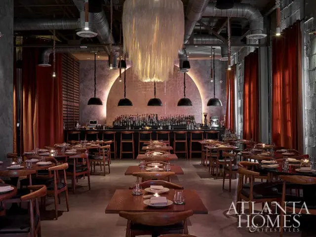 Restaurant interior with bar, tables, chairs, and red curtains. Atlanta Homes & Lifestyles logo in