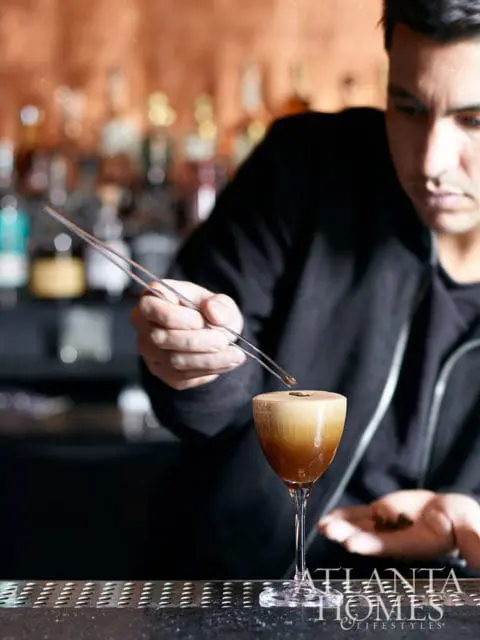 Bartender garnishing espresso martini with coffee beans.