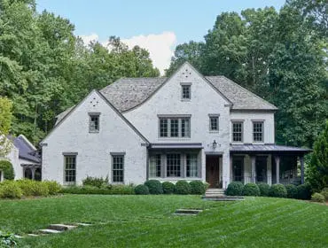 White brick house with gray roof, dark trim windows, and covered porch