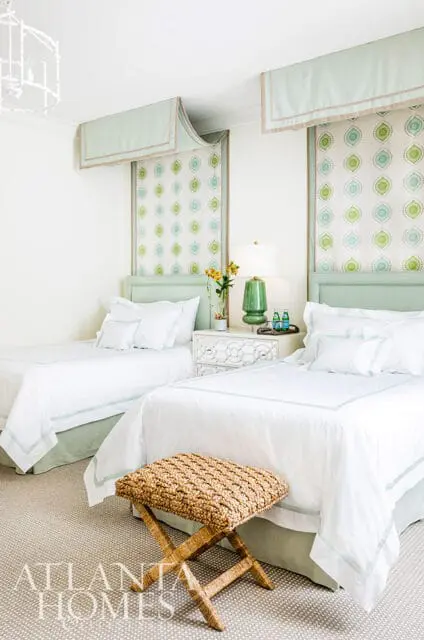 Bedroom with two twin beds, pale green headboards, white bedding, and patterned window treatments.