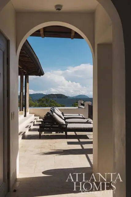 View through an archway to a patio with lounge chairs and ocean view