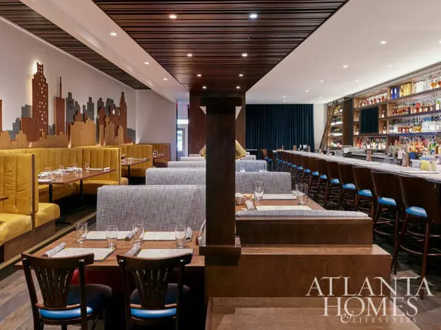 Restaurant dining area with yellow booths, gray banquettes, and a long bar with blue stools.