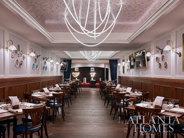 Restaurant dining room with wood paneled walls, white textured wallpaper, and tables set for dining.