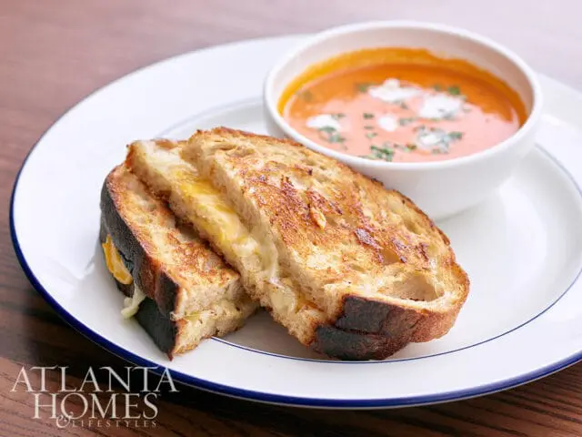 Atlanta Homes Lifestyles logo on a plate with grilled cheese and tomato soup