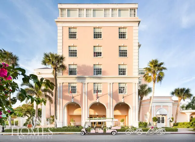 Peach hotel with arched entrance, palm trees, and pink golf cart