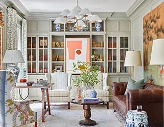 Living room with built-in bookshelves, tufted leather sofa, and patterned armchairs.