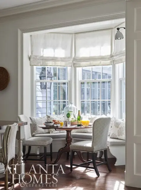Breakfast nook with bay window, banquette seating, and round table set with orange juice and