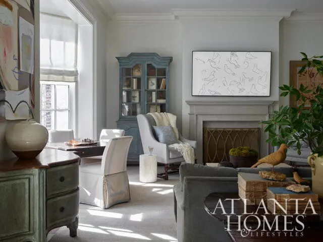 Living room with gray sofa, fireplace, blue cabinet, and artwork of birds.