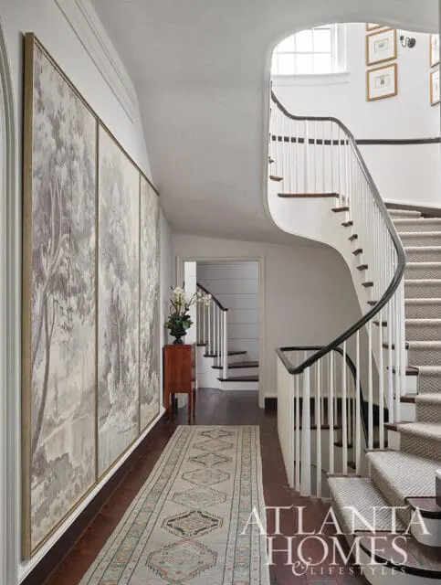 Hallway with large mural, curved staircase, and patterned runner