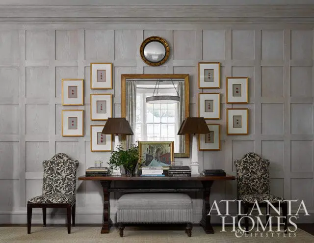 Entryway with paneled walls, console table, two chairs, and framed art.