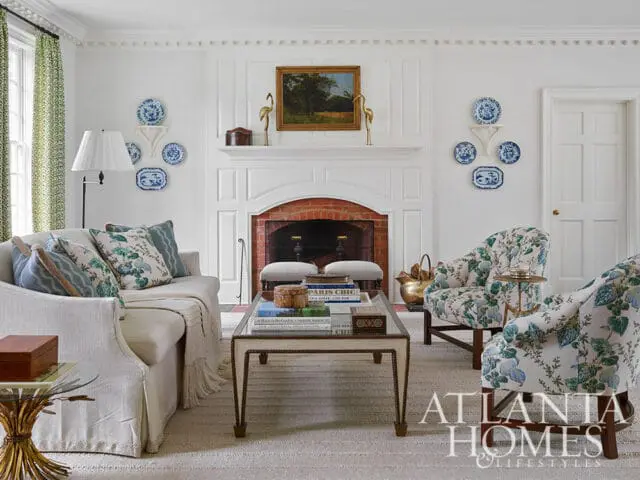 Living room with white sofa, floral armchairs, fireplace, and Atlanta Homes & Lifestyles logo.