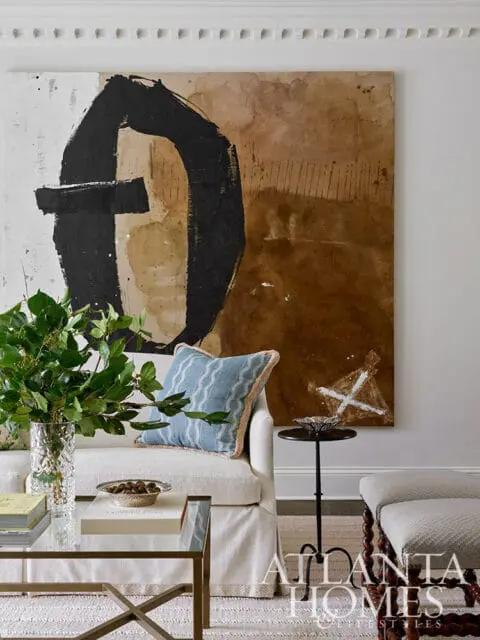 Living room with cream sofa, abstract art, and glass coffee table.