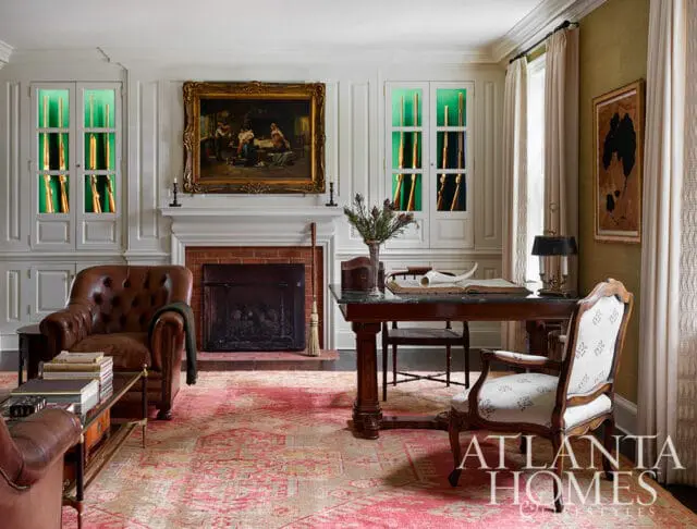 Brown leather armchair, fireplace, and desk in a room with a pink rug and Atlanta Homes &