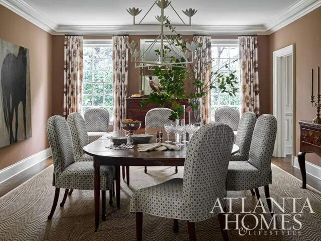 Dining room with brown walls, patterned curtains, and upholstered chairs around a wooden table.