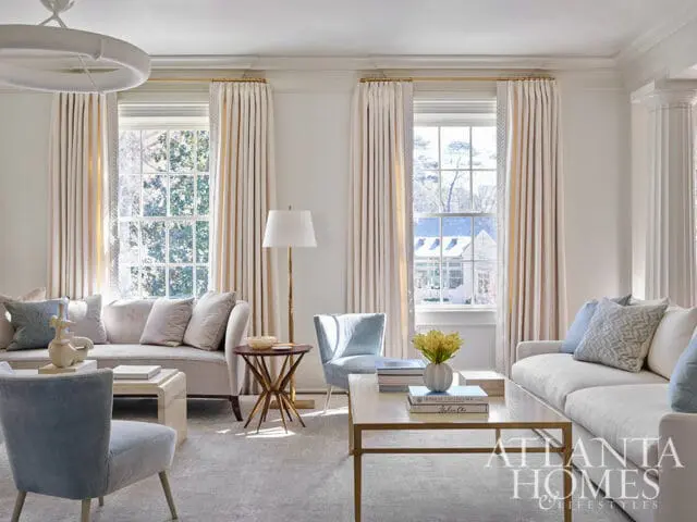 Living room with light gray carpet, cream curtains, and light blue accent chairs.