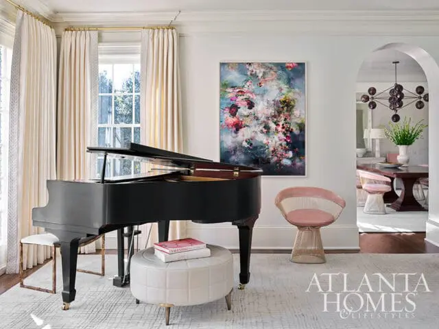 Grand piano in living room with abstract floral art and pink chair.