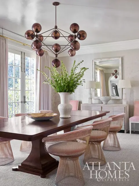 Dining room with dark wood table, pink wire chairs, and geometric chandelier.