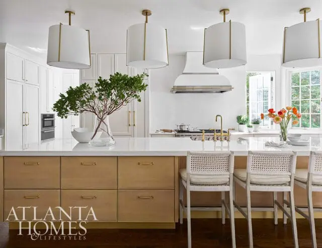 White kitchen with wood island, cane bar stools, and brass accents.