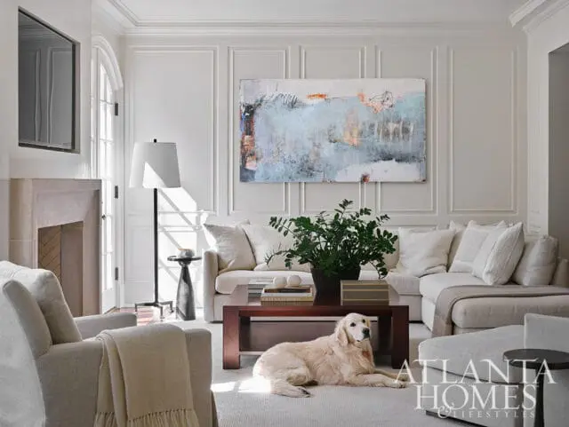 Living room with sectional sofa, armchair, fireplace, and abstract art.