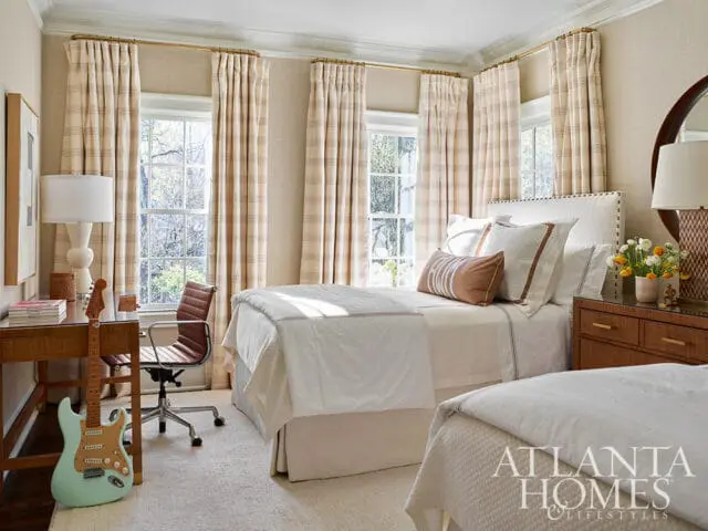 Bedroom with two beds, striped curtains, and a desk with a guitar.