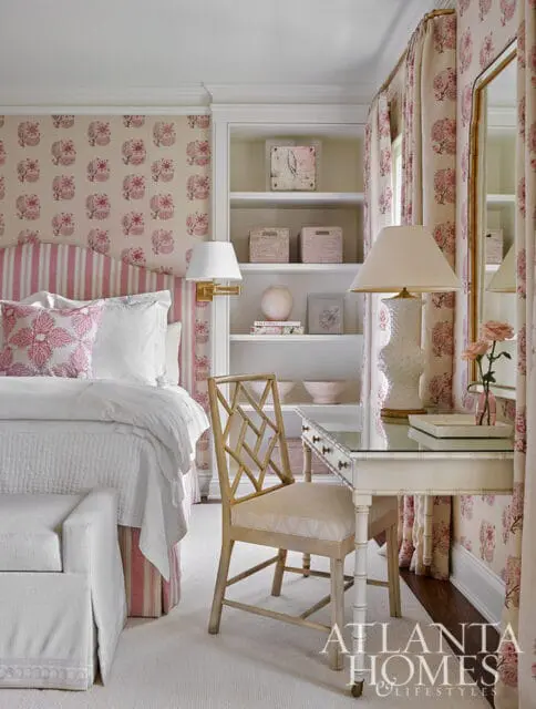 Bedroom with pink floral wallpaper, striped headboard, white bedding, and a desk with a geometric