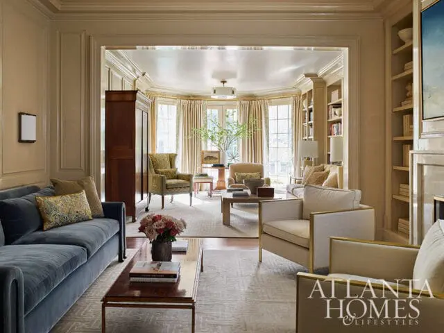 Living room with blue sofa, patterned armchairs, and built-in bookshelves.