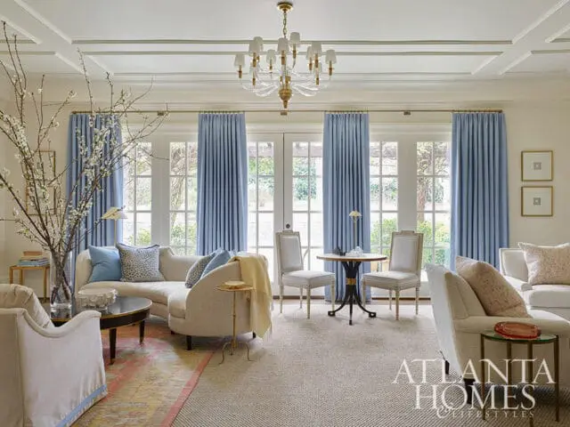 Living room with cream sectional sofa, blue curtains, and coffered ceiling.