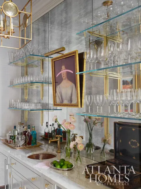 Bar with marble countertop, glass shelves, liquor bottles, and pink flowers.