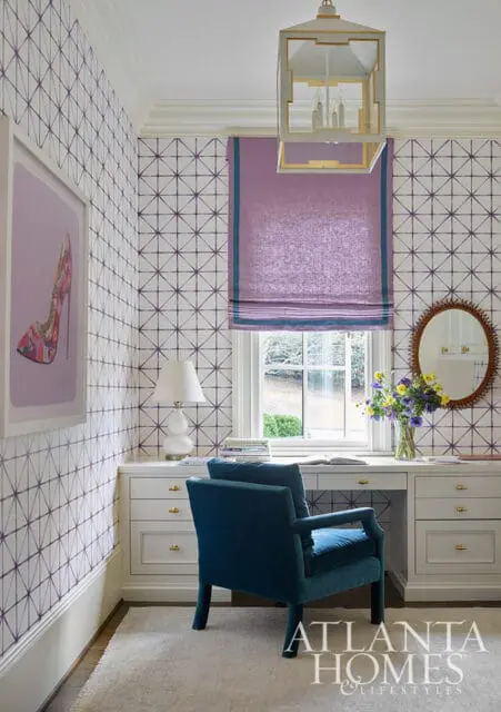 Desk with teal chair, purple geometric wallpaper, and framed shoe art.
