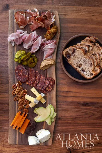 Charcuterie board with prosciutto, salami, cheese, pickles, nuts, and bread