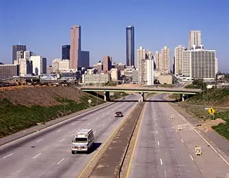 Highway leading to Atlanta skyline with tall buildings and a bridge over the road.