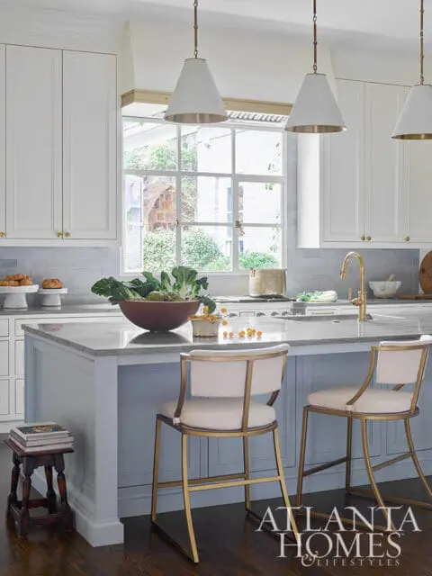White kitchen with gray tile backsplash, marble island, and brass accents.