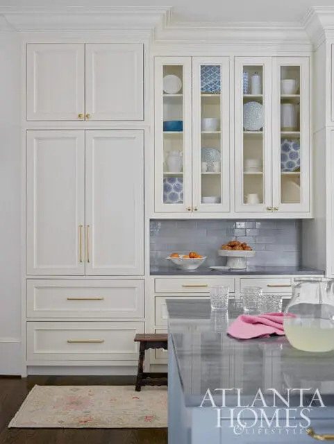 White kitchen cabinets with glass doors displaying blue and white patterned dishes, gray subway