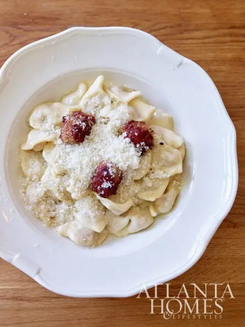 Plate of pasta with creamy sauce, topped with grated cheese and meatballs.
