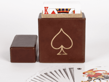 Brown leather card holder with gold spade emblem and playing cards