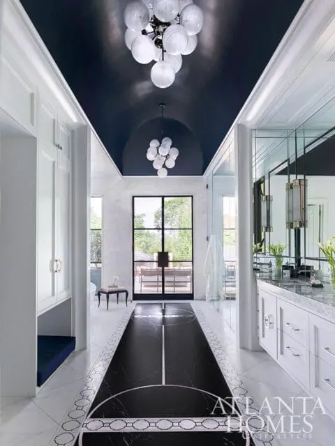 Hallway with dark marble floor inlay, white cabinetry, and glass doors leading outside.