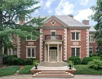 Red brick Georgian-style house with white trim, arched entryway, and manicured landscaping.