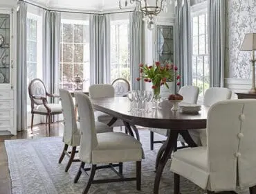 Dining room with oval table, upholstered chairs, buffet, and glass-front cabinet.