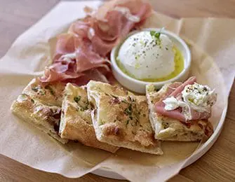 Burrata cheese with prosciutto and focaccia bread on a platter