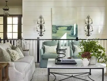 Living room with light gray sofa, sage green chairs, marble coffee table, and landscape painting.