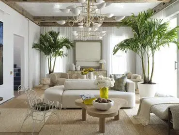Living room with curved sectional sofa, large artwork, palm trees, and modern chandelier.