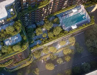 Aerial view of a modern apartment building with a rooftop pool and green spaces.