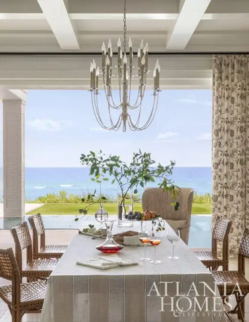 Dining room with ocean view, rattan chairs, and a chandelier.