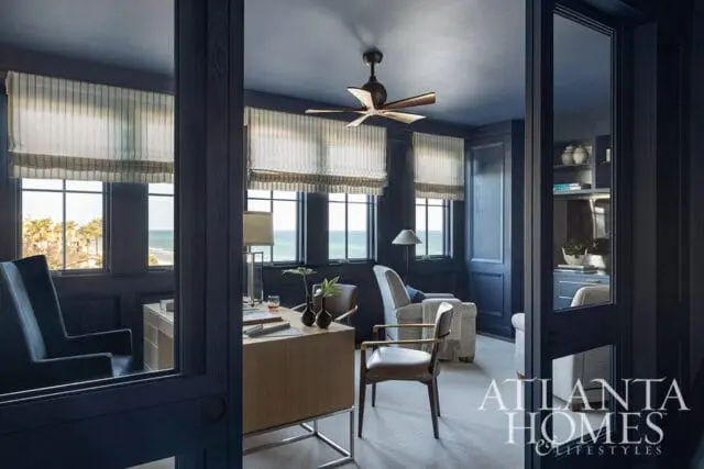 Dark blue office with ocean view, wood desk, leather chairs, and Atlanta Homes & Lifestyles logo.